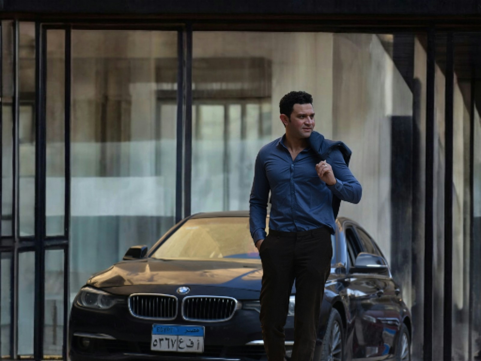 A man walks confidently by his car.